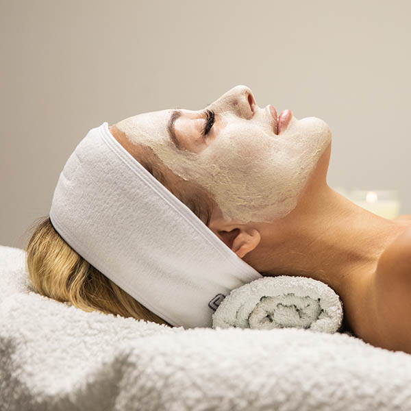 Beautiful woman with mask on face in spa beauty salon