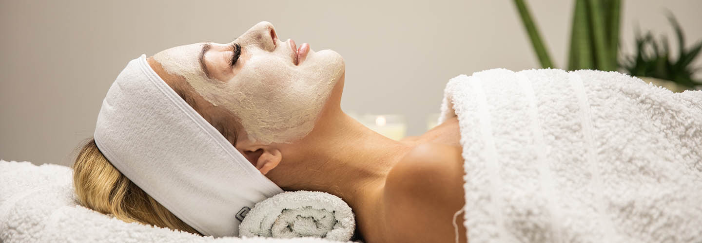 Beautiful woman with mask on face in spa beauty salon