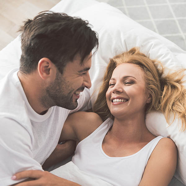 Happy loving couple having fun on bedding